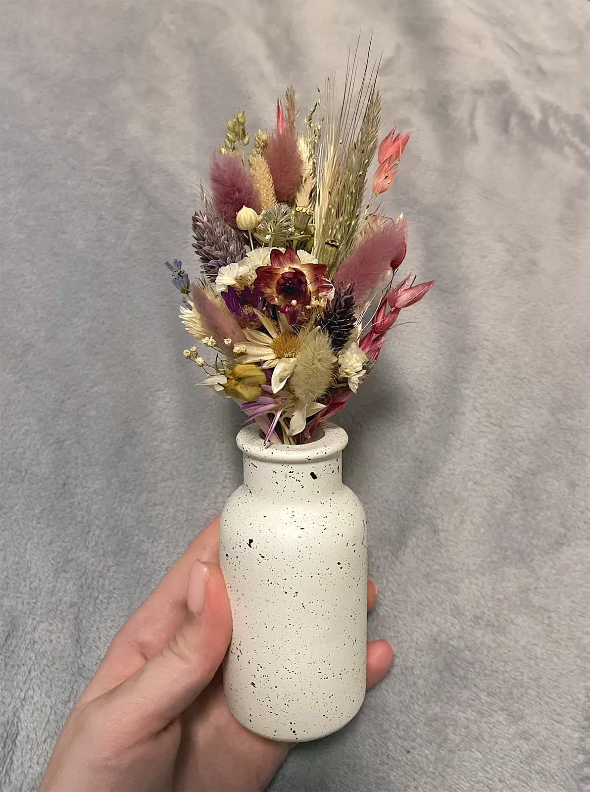 Маленька циліндрична гіпсова ваза з букетом рожево-лілових сухоцвітів