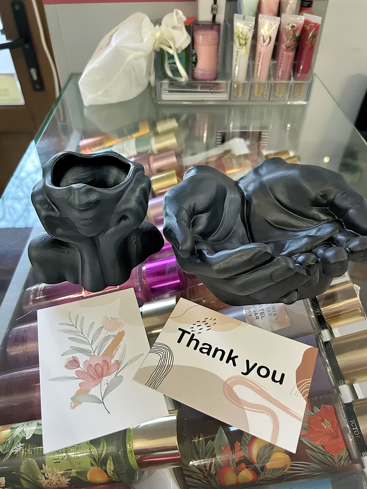 Чорні гіпсові кашпо Ніжна Мрійниця та Долоні на вітрині з косметикою